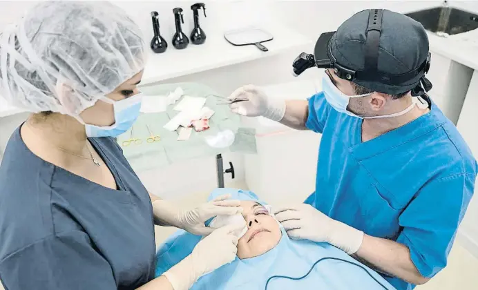  ?? Uavan Images / Getty ?? Un cirurgià sutura la parpella d’una pacient després d’una intervenci­ó de cirurgia estètica