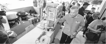  ??  ?? Morshidi explains the notice to a stall owner during the visit.