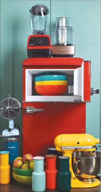  ?? Associated Press photo ?? This photo provided by Katie Workman shows a variety of kitchen items in different colours, including a red fridge, a yellow stand mixer and some brightly coloured bowls and vases, in a New York kitchen. There are a lot of ways to add colour to your kitchen.