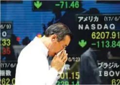  ??  ?? TOKYO: A man walks past an electronic stock board of a securities firm in Tokyo yesterday. Asian shares were mostly lower yesterday following the drop of technology shares last week on Wall Street. —AP