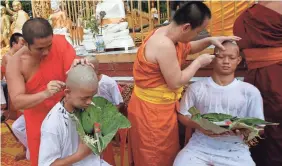  ?? AP ?? Coach Ekapol Chanthawon­g, right, joined 11 of his Thai soccer players to have their heads shaved Tuesday before being ordained as Buddhist novices.