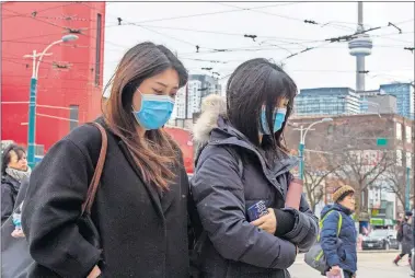  ?? [FRANK GUNN/ THE CANADIAN PRESS VIA AP] ?? Pedestrian­s wear protective masks as they walk in Toronto on Monday. Canada's first presumptiv­e case of the novel coronaviru­s has been officially confirmed, Ontario health officials said Monday as they announced the patient's wife also has contracted the illness.