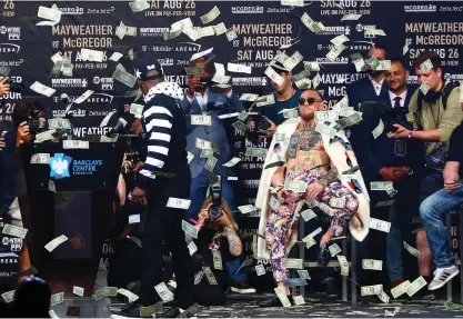  ?? FOTO: LEHTIKUVA/ AFP / MIKE STOBE ?? BILDTEXT. Floyd Mayweather ser på när pengar dalar ner över Conor McGregor under ett gemensamt presstillf­älle.