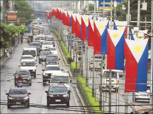  ?? EDD GUMBAN ?? Philippine flags are on display along Aguinaldo Highway in Dasmariñas, Cavite yesterday. Some people looking at the flags from the opposite direction of traffic have expressed confusion over the placement of the flags side by side while facing different directions. In a vertical position, the blue field must be on the left side of the viewer to indicate that the country is at peace.