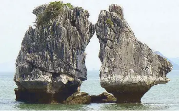  ??  ?? The Kissing Rock in Halong Bay, a World Heritage site. Some 1600 limestone islands and islets dot the Gulf of Tonkin. Many tourists mimic the rock—and kiss-kiss, hug-hug.