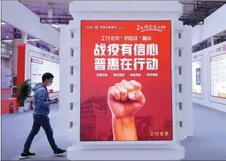  ?? CHEN XIAOGEN / FOR CHINA DAILY ?? A visitor walks past the booth of Industrial and Commercial Bank of China during a financing event in Beijing.