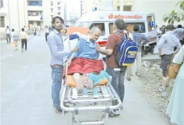  ?? — Reuters photo ?? A woman sits on a stretcher after she was evacuated from a government hospital due to fire, on the suburbs of Mumbai, India.