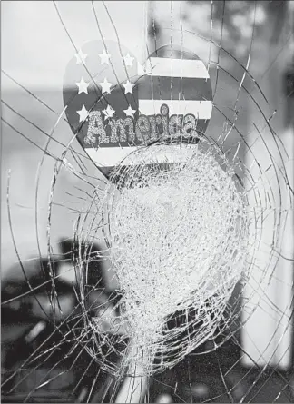  ?? ALYSSA SCHUKAR/THE NEW YORK TIMES ?? A sticker reading “America” is seen Aug. 25 in the window of a damaged business in Kenosha, Wisconsin.