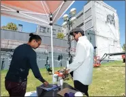  ?? NWA Democrat-Gazette/ANDY SHUPE ?? Artists Tenchi (left) and Alexis Diaz speak Saturday while working on a mural at College Avenue and Center Street in Fayettevil­le.