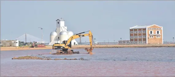  ??  ?? Una retroexcav­adora trabaja en la reducción a cota 82 de la altura del muro de piedra que separa la playa del río abierto.