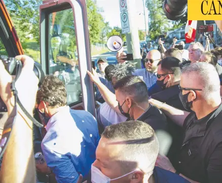  ?? DEREK RUTTAN / POSTMEDIA NEWS ?? Gravel thrown from a group of protesters strikes Liberal Leader Justin Trudeau in the back and head as he boards his bus at the end of a campaign stop at the London Co-operative Brewing Company in London, Ont., on Monday.