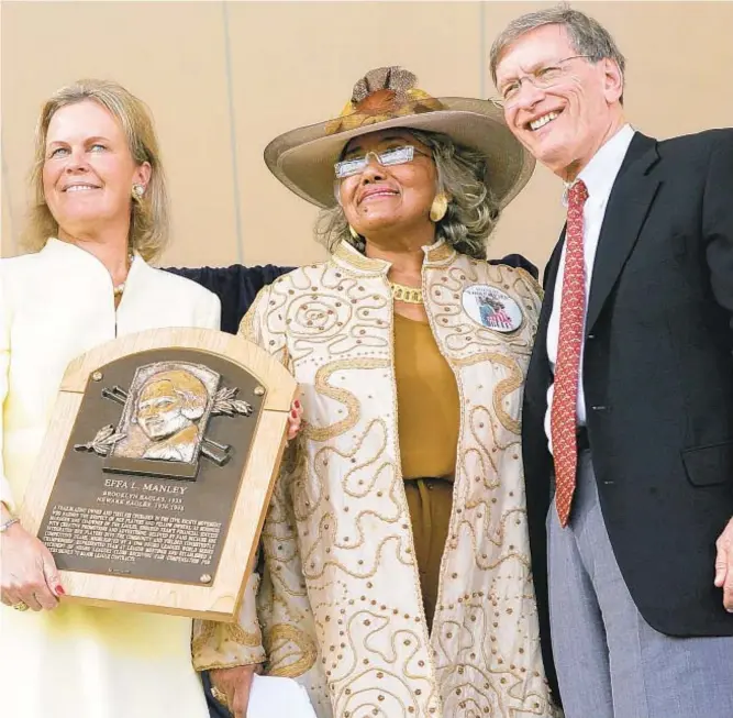  ?? GETTY & AP ?? When Effa Manley was inducted into the Baseball Hall of Fame in 2006, her niece, Connie Brooks (second from r.), accepted her plaque from then-commission­er Bud Selig (r.), Hall president Dale Petroskey (l.) and chairperso­n Jane Forbes Clark. Three decades prior, Manley and former Brooklyn Dodger Don Newcombe (inset) looked through scrapbooks holding memories of her time with husband Abe as owners of the Newark Eagles, a career that made Effa one of baseball’s first female pioneers.