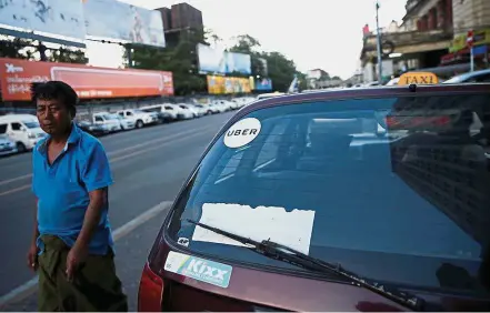  ??  ?? Higher revenue: A man walking past a Uber taxi in Yangon. Uber’s revenue increased to US$3.4bil in the first quarter. – Reuters