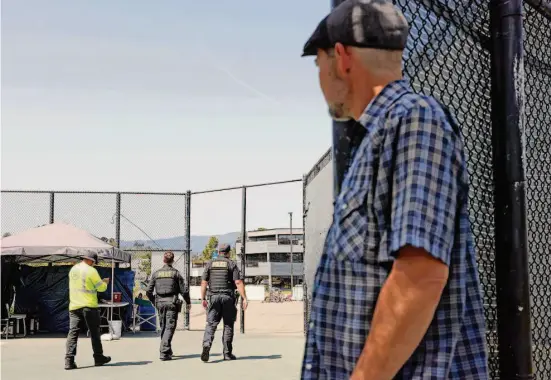  ?? Santiago Mejia/The Chronicle ?? Arthur Bruce watches Sausalito officers leave the Marinship Tennis Courts sanctioned encampment on April 6. Police temporaril­y barred Bruce from entering.