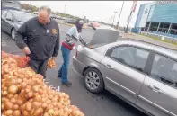  ??  ?? Volunteers distribute onions at Rentschler Field for a Foodshare distributi­on of 35,000 pounds of food.