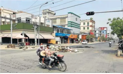  ?? EFE ?? Dos personas pasan en moto ante establecim­ientos cerrados durante la “huelga de silencio”, ayer en Mandalay.
