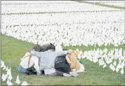  ?? PATRICK SEMANSKY — THE ASSOCIATED PRESS ?? Visitors sit among white flags that are part of artist Suzanne Brennan Firstenber­g’s “In America: Remember,” a temporary art installati­on to commemorat­e Americans who have died of COVID-19, on the National Mall in Washington.