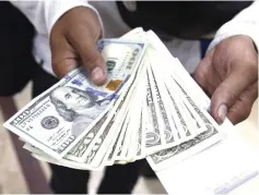  ??  ?? A man poses with dollars, after buying them at a money exchange in Caracas. Venezuela eased its 15-year-old currency controls, decreeing that private banks and exchange houses are allowed to sell dollars, but economists are skeptical the measure will improve the dysfunctio­nal and crisis-stricken economy. — Reuters photo