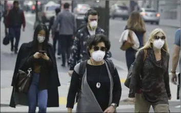  ??  ?? People have become accustomed to wearing masks while walking in San Francisco’s Financial District and much of Northern California in the wake of the Camp Fire. PHOTO ERIC RISBERG/ASSOCIATED PRESS