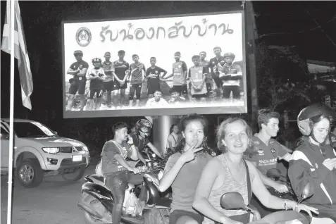  ?? AGENCE FRANCE PRESSE ?? Motorists pass a billboard with a photograph showing members of the Thai children's football team "Wild Boar" and their coach with a message "welcome home brothers" displayed in Chiang Rai as the boys and their coach were all rescued in the ThamLuang...
