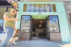  ?? ?? A pedestrian walks his dog by Dogue, a dog restaurant in San Francisco. For $75 per pup, doggie diners get a multiple-course “bone appétit” meal featuring such dishes as chicken skin waffles and filet mignon steak tartar with quail egg.