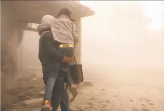  ?? Syrian Defense White Helmets ?? A member of the Syrian Civil Defense group, known as the White Helmets, carries a girl in Ghouta who was wounded during air strikes and shelling by Syrian government forces.