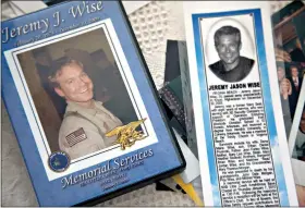  ?? (Special to the News-Times) ?? In this photo taken Jan. 24, 2012, the image of former Navy Seal Jeremy Wise is shown on the cover of a video of his 2009 memorial service and a newspaper obit displayed at his sister’s home in Prescott, Ark.