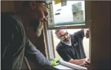  ??  ?? Stonepaint­er (left) and Darin Dell, owner of Especially Windows and Remodeling, remove part of a window frame.