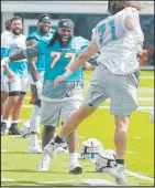  ?? Marta Lavandier The Associated Press ?? Dolphins offensive lineman Blaise Andries (71) cheers with defensive tackle John Jenkins at the start of drills Saturday at training camp.