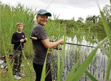  ?? FOTO: ELENA ZELLE ?? Bastian Wenholt (links) und Fabian Behnke angeln an einem See in Verden im Bundesland Niedersach­sen. Mit ihrem Angelverei­n gehen Bastian und Fabian etwa einmal im Monat Fische fangen.