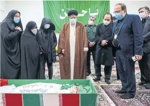  ?? MICHEL ZECLER/GS GROUP MIZAN NEWS AGENCY/AFP VIA GETTY IMAGES ?? Iran’s judiciary chief Ayatollah Ebrahim Raisi, centre, pays respects to the body of slain nuclear scientist Mohsen Fakhrizade­h among his family in Tehran on Saturday.