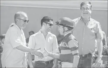  ?? Benoit Photo ?? KOSTA HRONIS, left, congratula­tes jockey Tyler Baze after a victory at Del Mar this summer. Hronis is co-owner of Accelerate and Catalina Cruiser, both trained by John Sadler, right.