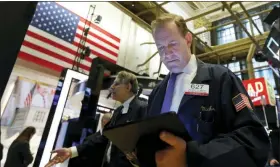  ?? AP PHOTO/RICHARD DREW ?? Trader Michael Smyth, right, works on the floor of the New York Stock Exchange on Friday.
