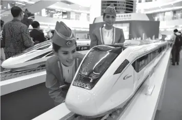  ?? AGENCE FRANCE PRESS ?? Indonesian models look at scale models of Chinese-made bullet trains on exhibition at a shopping mall in Jakarta.