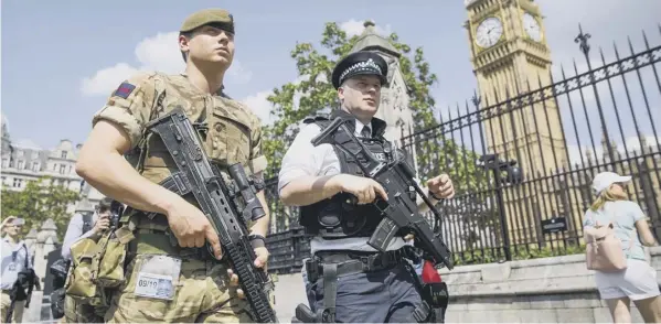  ?? PICTURE: TOLGA AKMEN/LNP ?? A soldier joins an armed police officer on patrol around the Palace of Westminste­r after the terror threat level was raised to ‘critical’