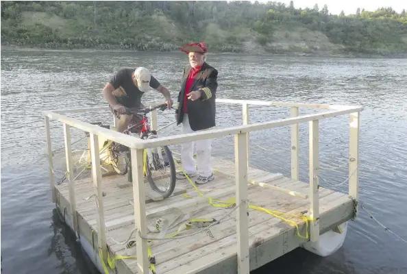  ?? ROBERT SIESWERDA ?? Nick Lees discusses modificati­ons to a Sourdough Raft Race pedal-powered raft with Gord Laird after the craft ran aground shortly being launched Saturday night at the 50th Street boat launch.