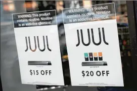  ?? GETTY IMAGES ?? Signs in the window of a Smoke Depot advertise electronic cigarettes and pods by Juul, the nation’s largest maker of e-cigarette products. The FDA has ordered e-cigarette product makers to devise a plan to keep their devices away from minors.