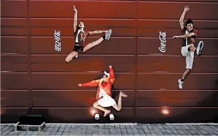  ?? ELIZABETH DALZIEL/ASSOCIATED PRESS 2008 ?? A young girl mimics the pose of Chinese Olympic athletes depicted in Coca-Cola advertisin­g, at the Olympic green in Beijing.