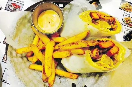  ??  ?? Apna Chaat’s chicken tikka kathi roll comes with a surprising­ly good side of fries.
