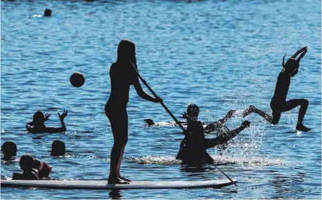  ?? FOTOS: DPA ?? Schwimmst du noch oder paddelst du schon? Badegäste und Wasserspor­tler genießen das sommerlich­e Wetter – jeder auf seine Weise.