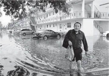  ?? CARL JUSTE cjuste@miamiheral­d.com ?? Homero Giviria, 76, walks barefoot to his job at Aventura Mall with his dry shoes in a plastic bag in the Biscayne Lake Gardens apartment complex in Aventura on December 23, 2019.