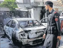  ?? AGENCIES ?? Left: People comfort a family member of a policeman killed during a gunbattle at the Chinese consulate in Karachi on Friday. Top: A paramilita­ry soldier walks past a wreckages of cars at the site.