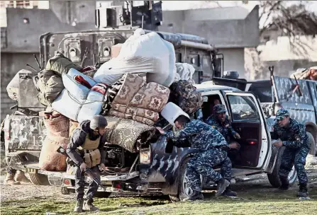  ??  ?? Heavy duty: Iraqi Federal police members taking cover as smoke billows from a big explosion during fighting between Iraqi troops and fighters of the Islamic State group in Mosul. — AFP