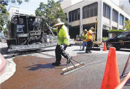  ?? U-T ?? A crew seals a street downtown with slurry. San Diego has repaired 1,700 miles of its streets in total — more than half of San Diego’s 3,000-mile street network — since Mayor Kevin Faulconer took office in 2014 and made infrastruc­ture his chief priority.