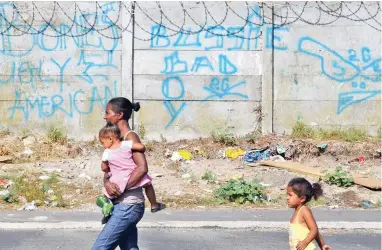  ?? PICTURE: CINDY WAXA/AFRICAN NEWS AGENCY (ANA) ?? ANGUISH: A mother and her two young children walk past a gang sign. The writer, who lives in Hanover Park, says violence in their community robs people of their human rights.