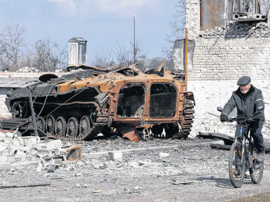  ?? REUTERS ?? A local resident rides a bicycle past a charred armoured vehicle during Ukraine-russia conflict in the separatist-controlled town of Volnovakha in the Donetsk region, Ukraine, on March 15.