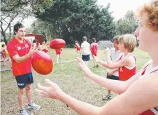  ??  ?? A young Palm Beach Currumbin student Jesse Joyce (centre right) handballs to former Suns player Marc Lock in 2010.