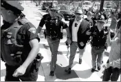  ?? ASSOCIATED PRESS ?? IN THIS JULY 19, 2016, FILE PHOTO, Alex Jones (center right) is escorted by police out of a crowd of protesters outside the Republican convention in Cleveland.