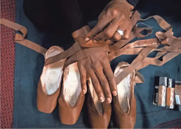  ?? PHOTOS BY ARIEL COBBERT/THE COMMERCIAL APPEAL ?? Prima ballerina Paunika Jones pancakes her pointe shoes with makeup to match her skin in a dressing room at the Cannon Center For The Performing Arts in Memphis on Nov. 11. Dancers of color normally have to paint their pink pointe shoes with foundation to get an accurate skin tone match. At top: Collage Dance Collective dancers perform the majestic second act of Swan Lake.