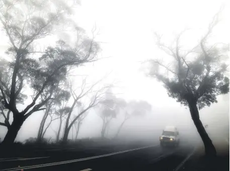 ??  ?? A car makes its way through thick fog mixed with bushfire smoke in the Ruined Castle area of the Blue Mountains, some 75 kilometers from Sydney, Jan. 11, 2020.